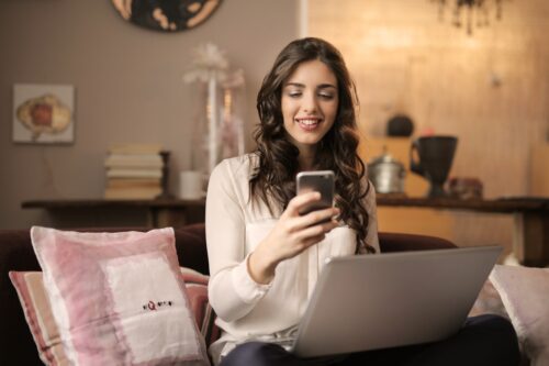 Woman looking at phone and laptop