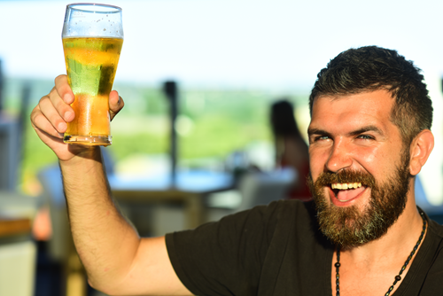 Photo of a man cheersing with a beer